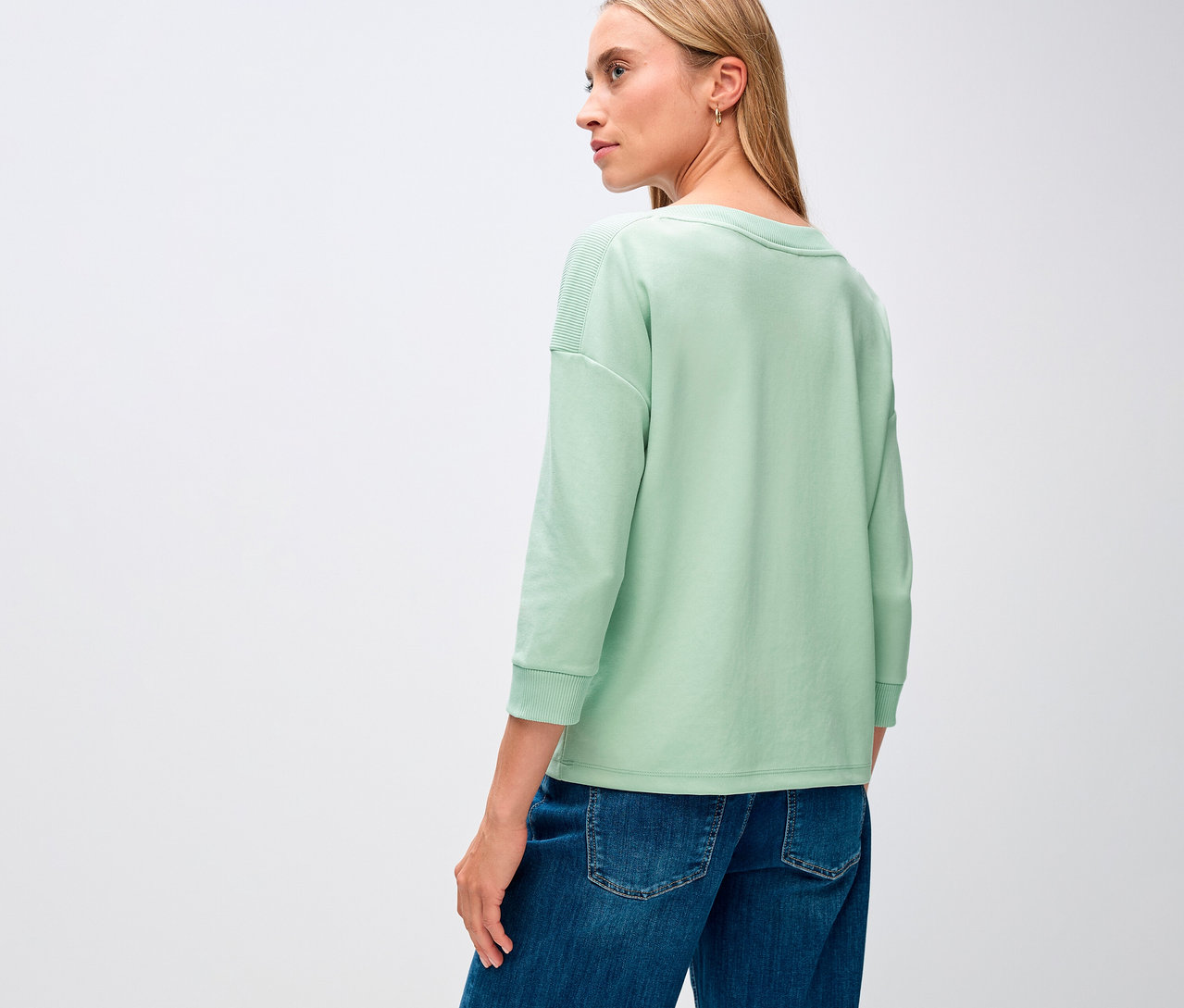 Žena má na sobě šalvějově zelené tričko Street One s žebrovaným detailem.