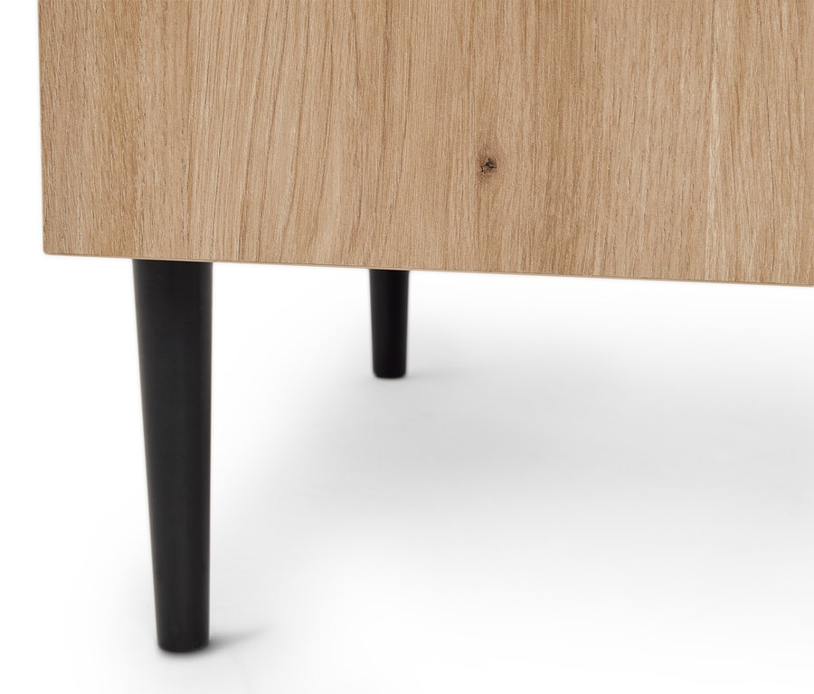 Detailní záběr na světlou dřevěnou skříňku se dvěma černými nohami.