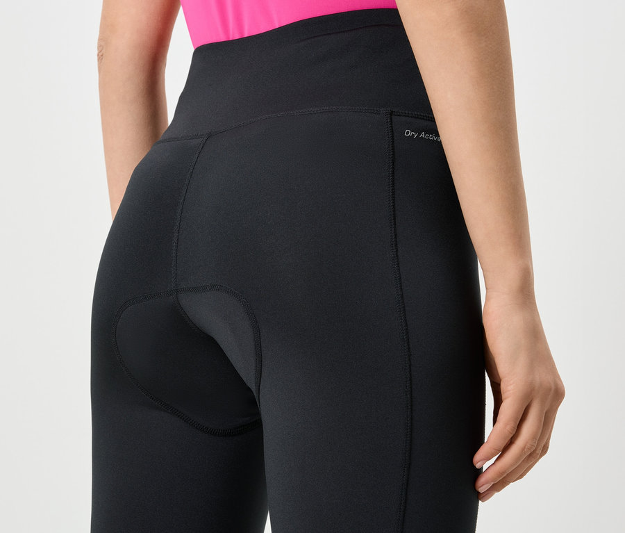 Detailní záběr na zadní část ženy v černých legínách s vysokým pasem a logem „Dry Active“.