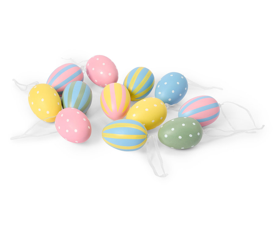Na bílém pozadí leží několik pastelových velikonočních vajíček s tečkami a pruhy.