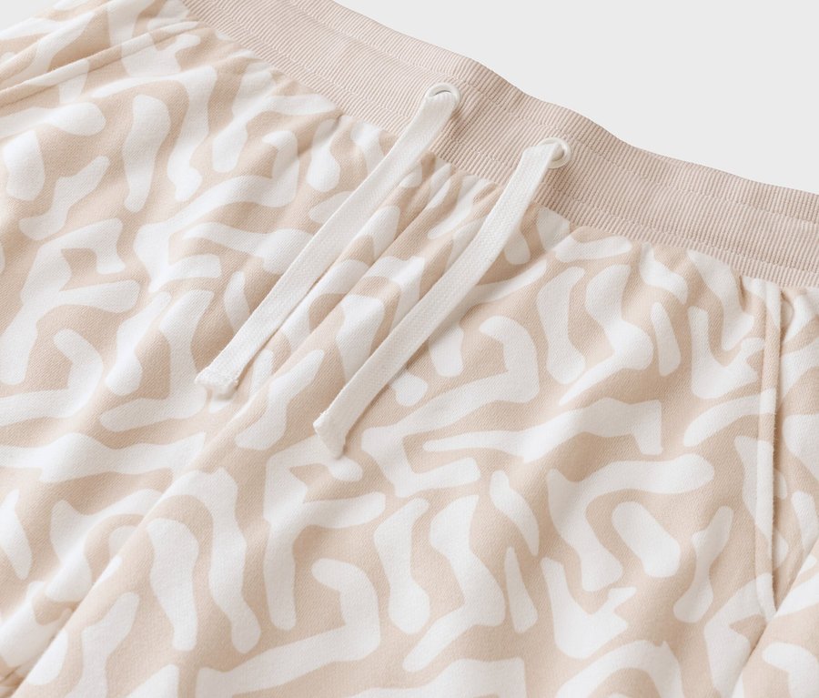 Detail béžových vzorovaných kalhot s bílou stahovací šňůrkou.