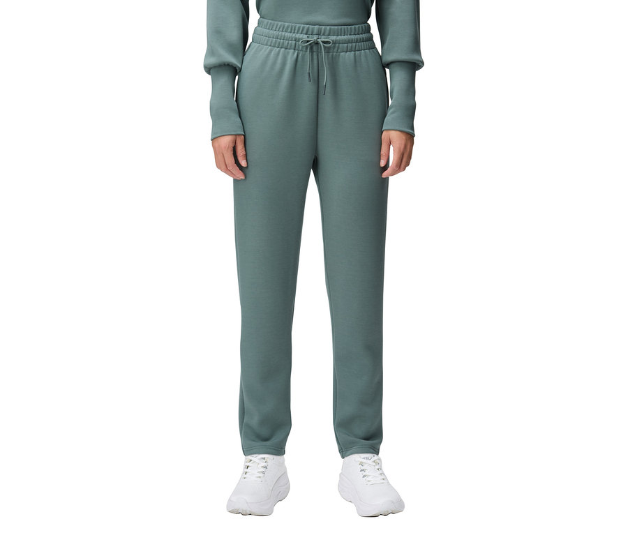 Osoba má na sobě zelené tepláky a bílé tenisky.