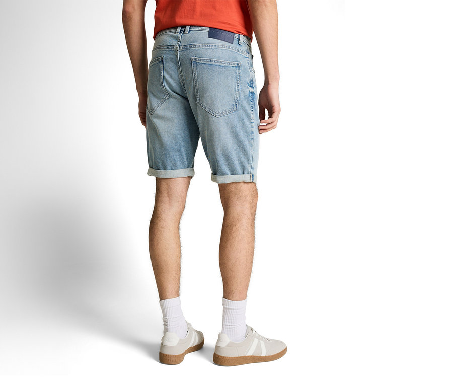 Muž zezadu v džínových šortkách Tom Tailor TTJOSH REGULAR SLIM, light stone blue denim, bílých ponožkách a teniskách.