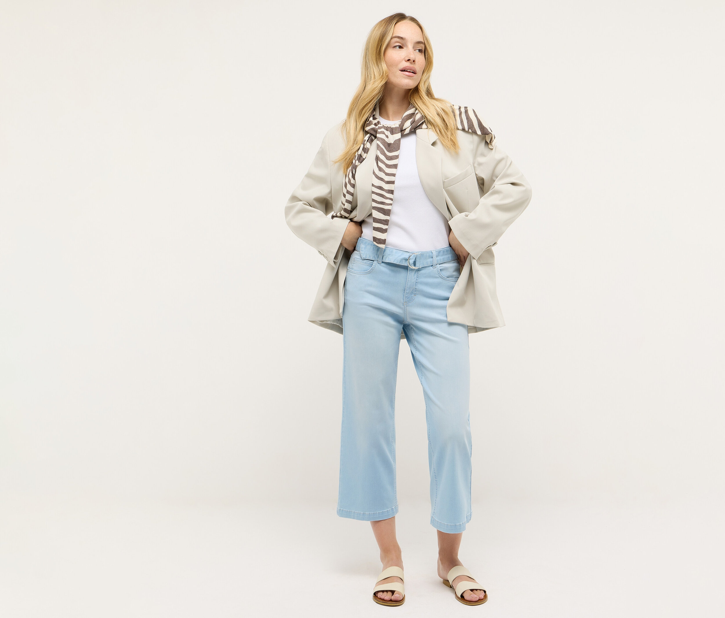 Žena stojí a má na sobě džíny Angels »Linn City« cropped, bleached blue, bílé tričko, blejzr a šálu.