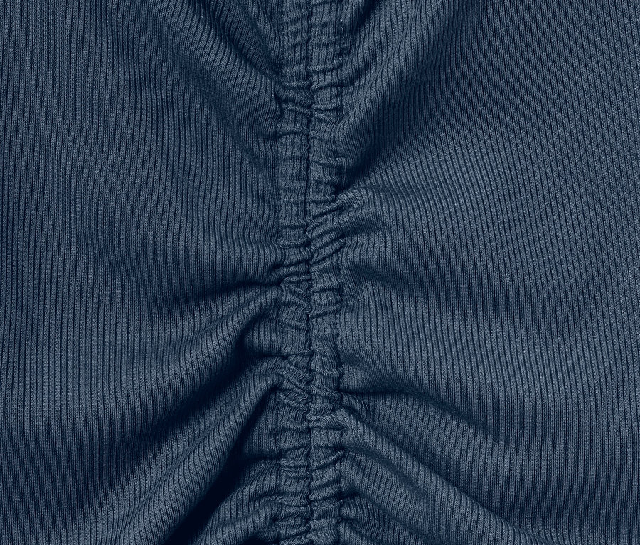 Detail modrého sportovního trika s nařasením uprostřed.