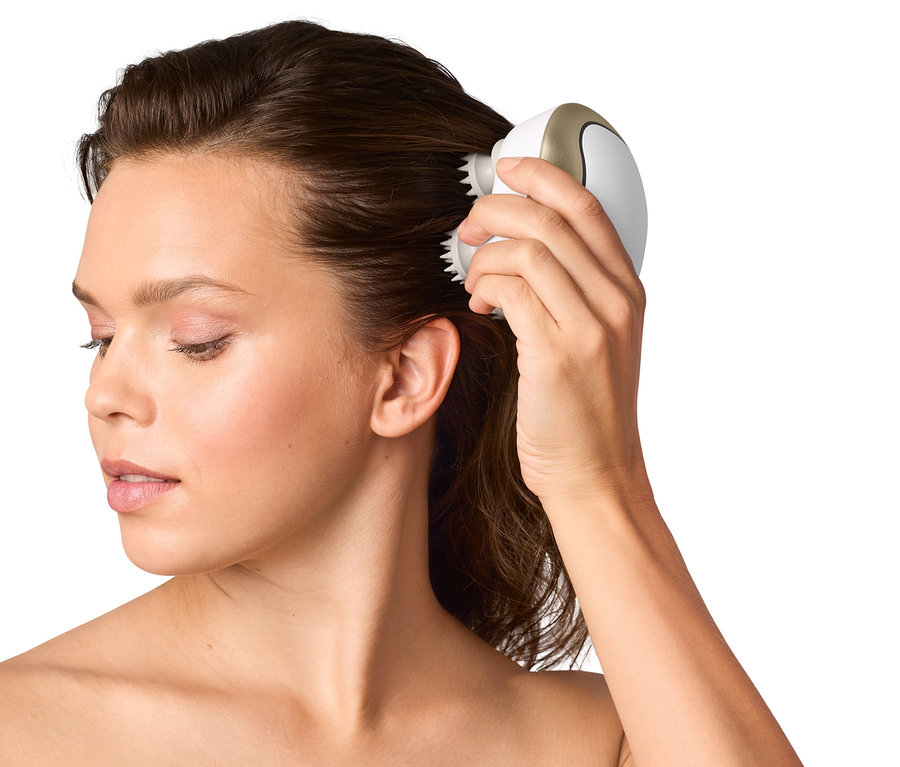 Žena používá vodotěsný masážní přístroj na vlasy.