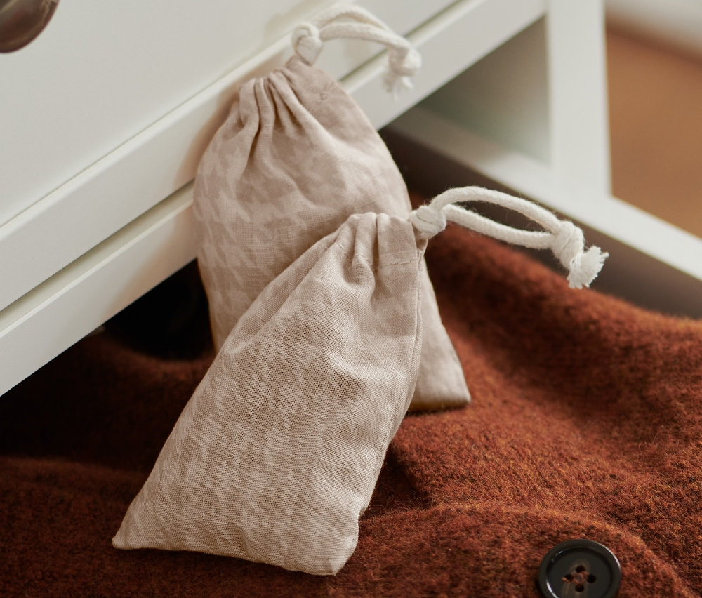 Dva sáčky s cedrovými hoblinami leží na hnědém svetru v otevřené zásuvce.