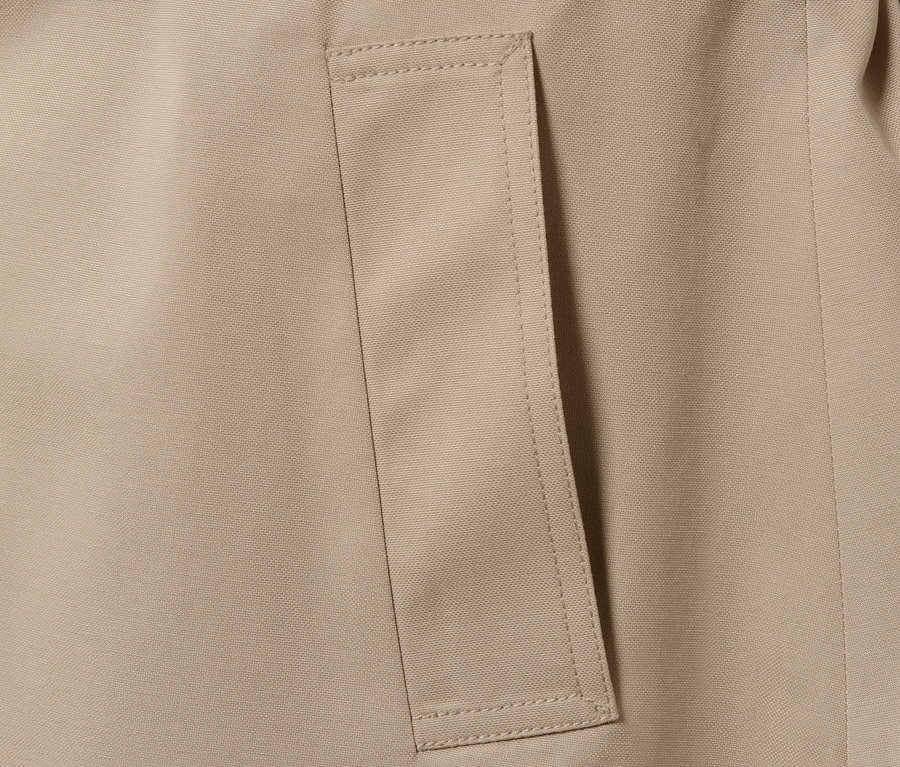 Detail béžového trenčkotu s kapsou.