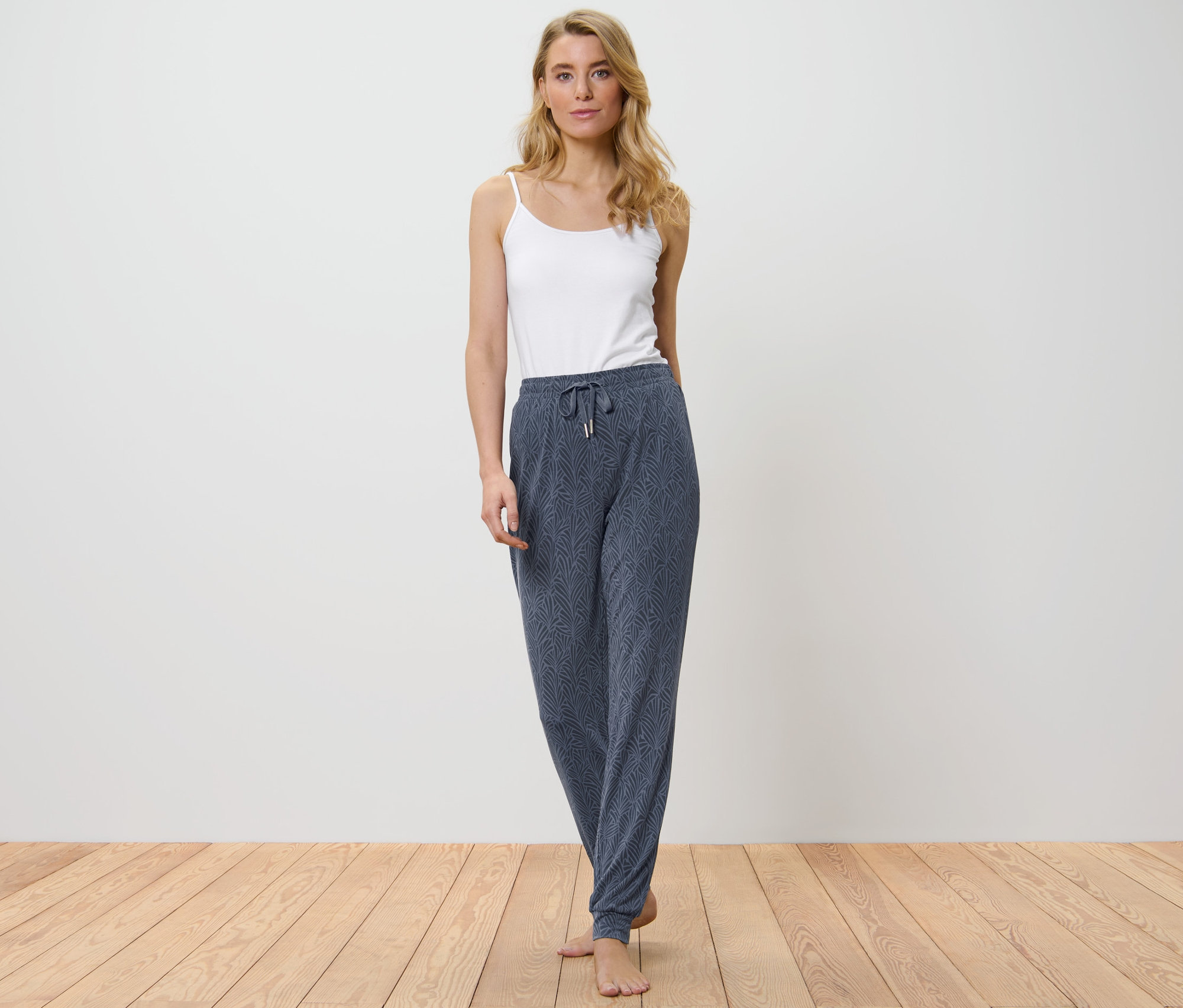 Žena má na sobě pyžamové kalhoty a bílý top.