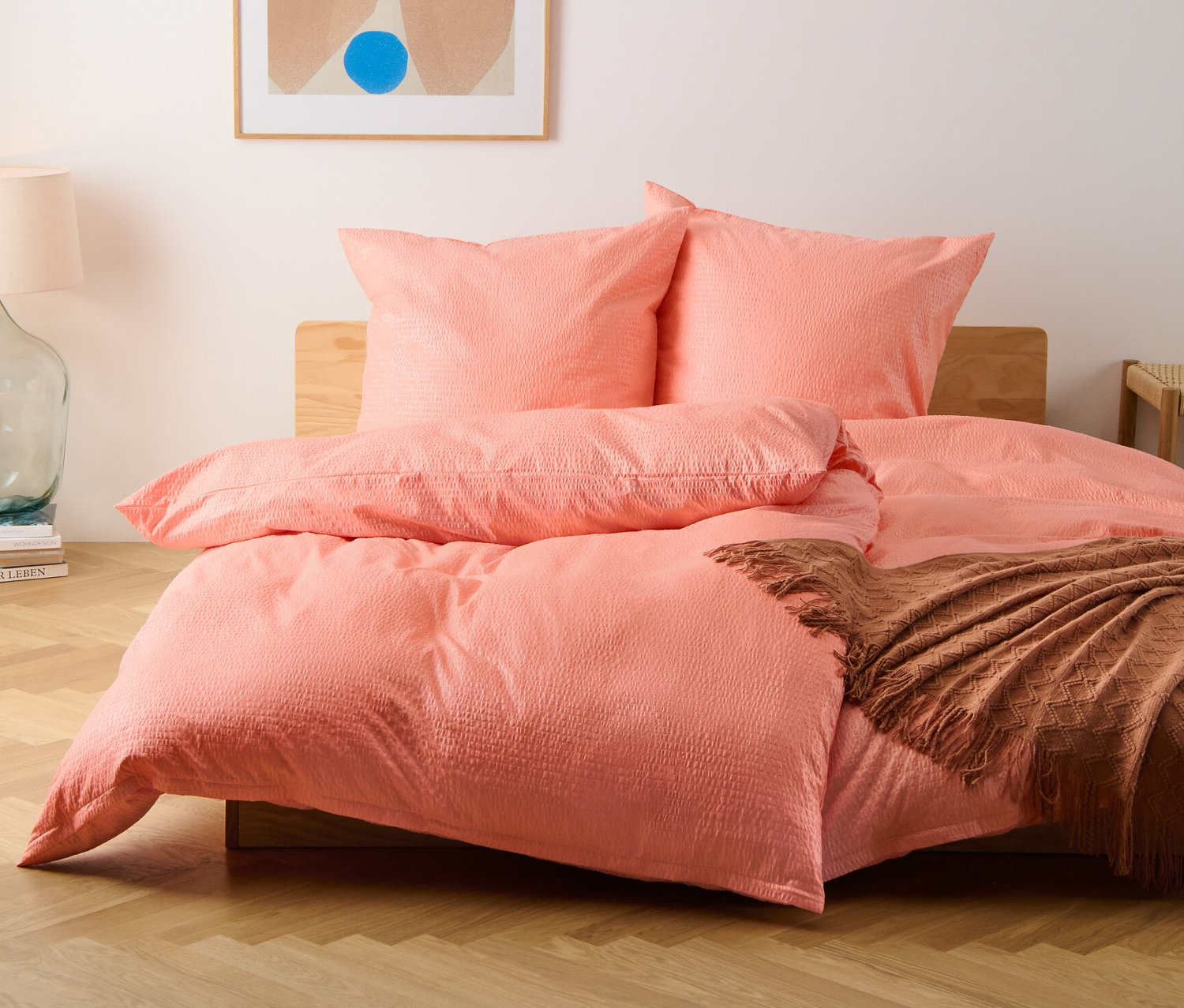 Čelní pohled na postel s krepovým povlečením standardní a nadměrné velikosti v broskvové barvě.