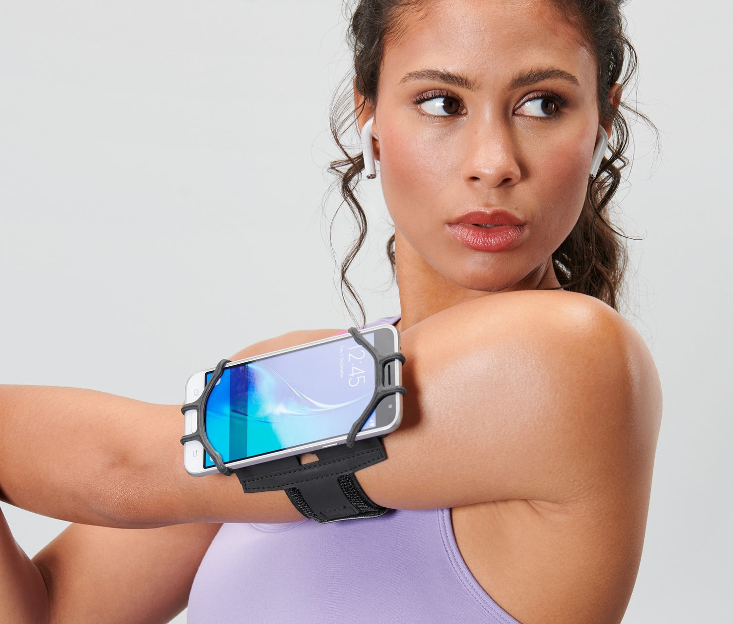 Žena protahuje ruku a má na paži sportovní náramek na chytrý telefon.