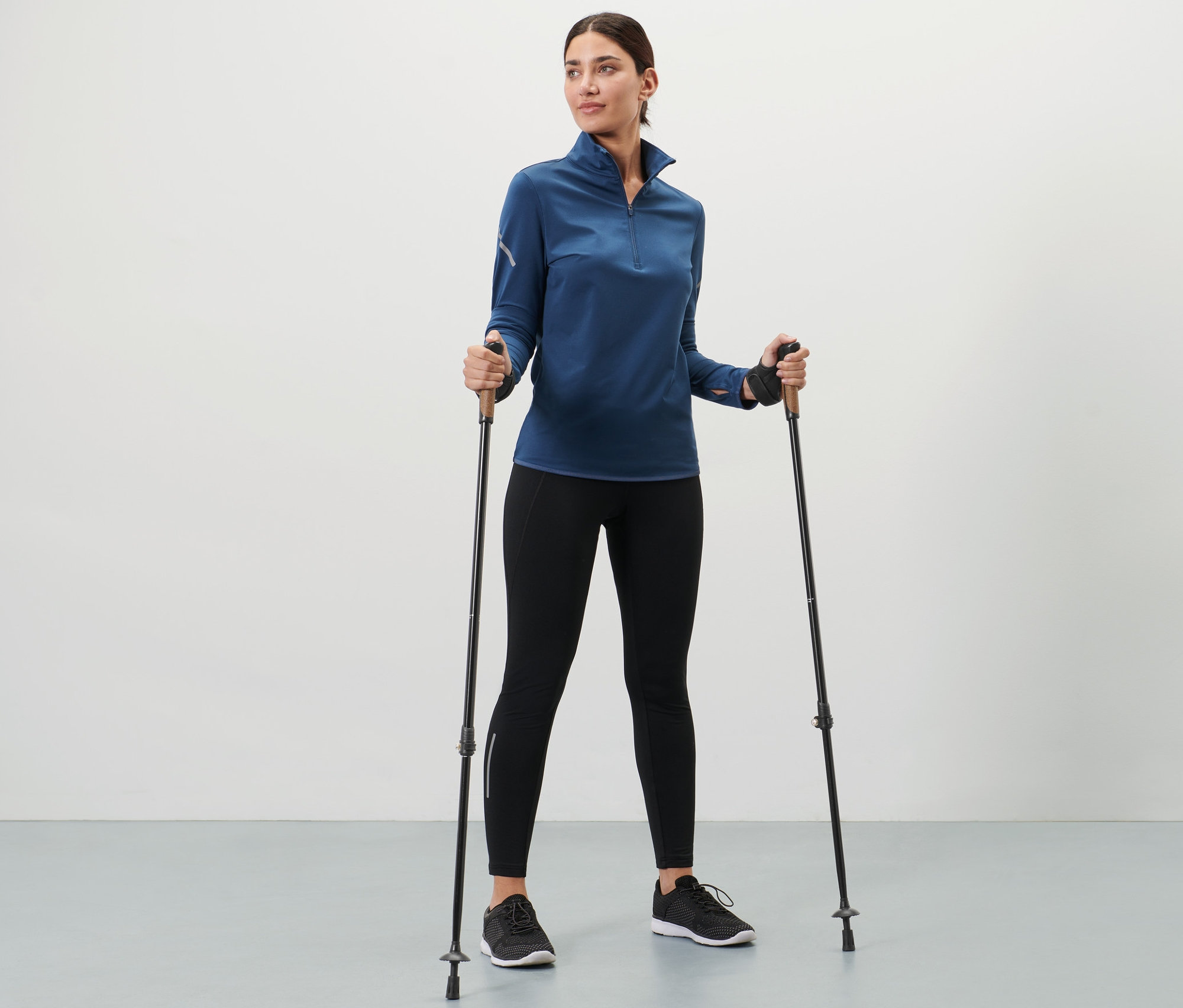 Žena drží teleskopické vycházkové hole.