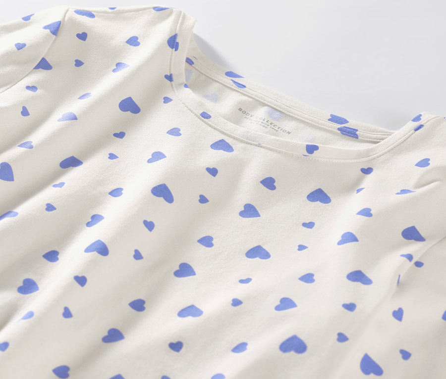 Detail bílého pyžama se světle modrými srdíčky.