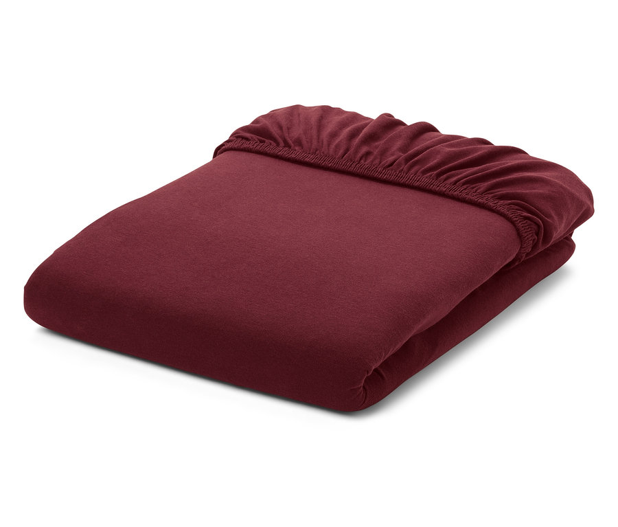 Složená, bordó prostěradla s gumou na bílém pozadí.