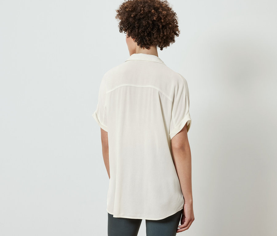 Zezadu žena v krémově bílé halence.