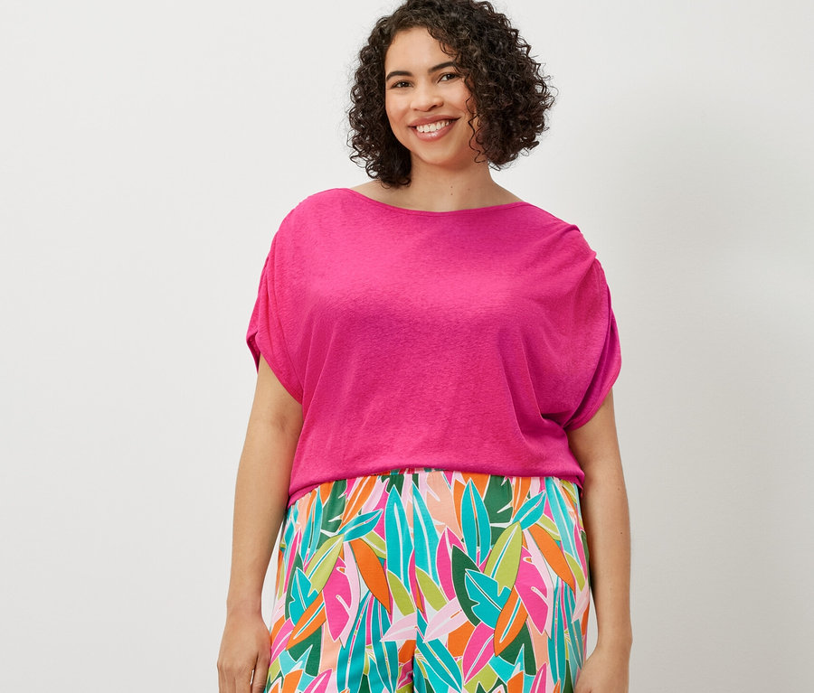 Žena má na sobě tričko ze směsi lnu a kalhoty se širokými nohavicemi s potiskem.