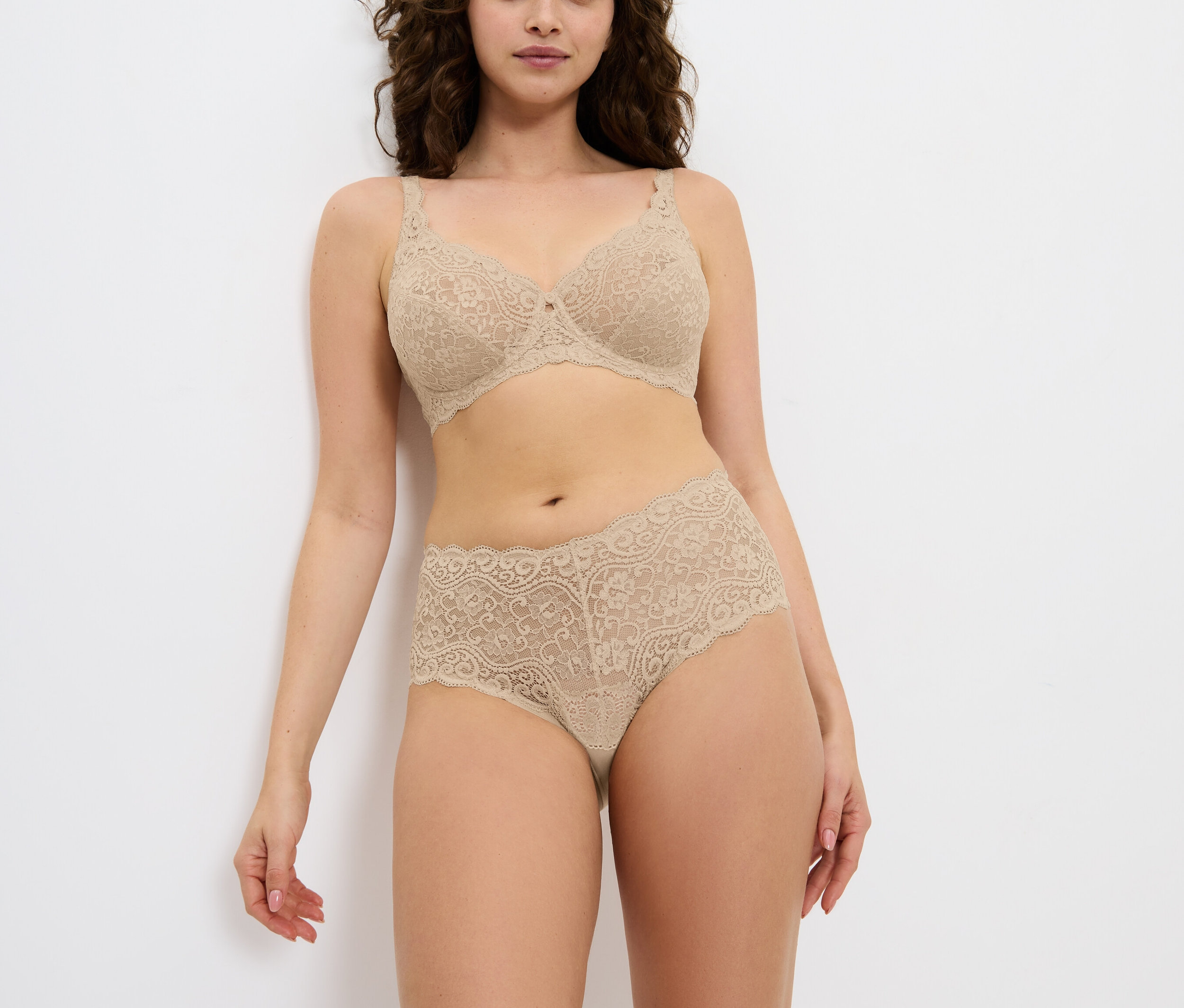 Žena pózuje ve spodním prádle s květinovou krajkou.