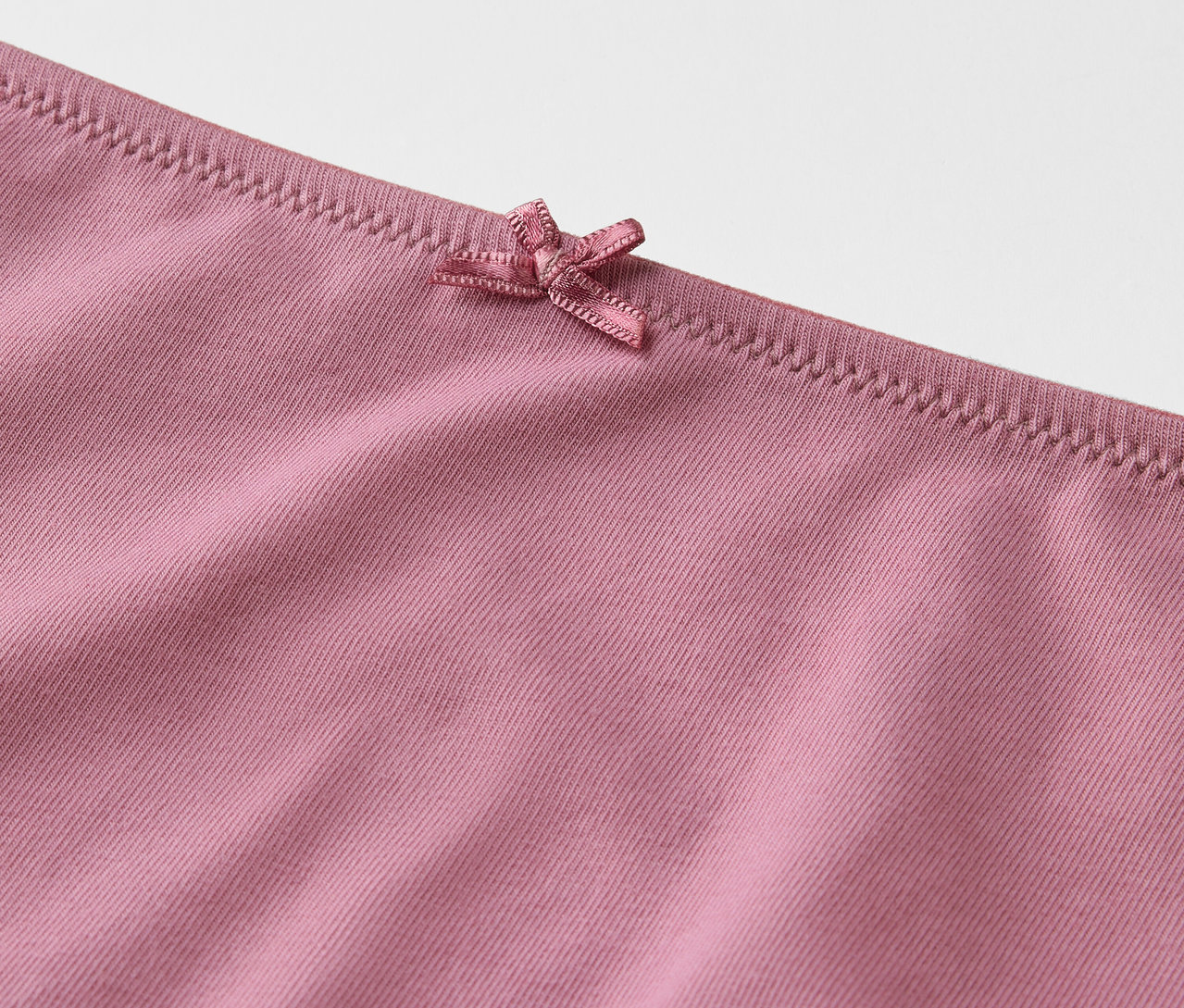 Detail růžových kalhotek s mašlí.