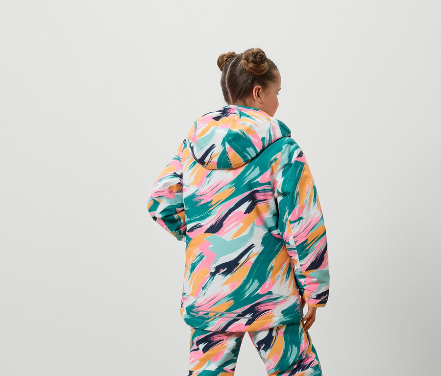 Zezadu je vidět dívka v barevné bundě a kalhotách.