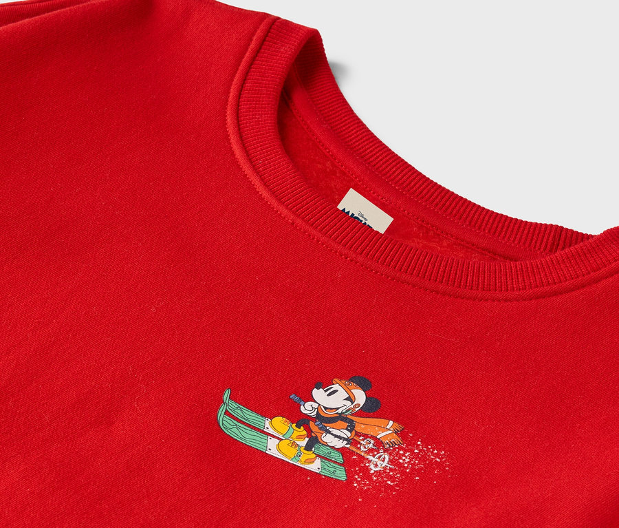Červený svetr s Mickey Mousem na lyžích.