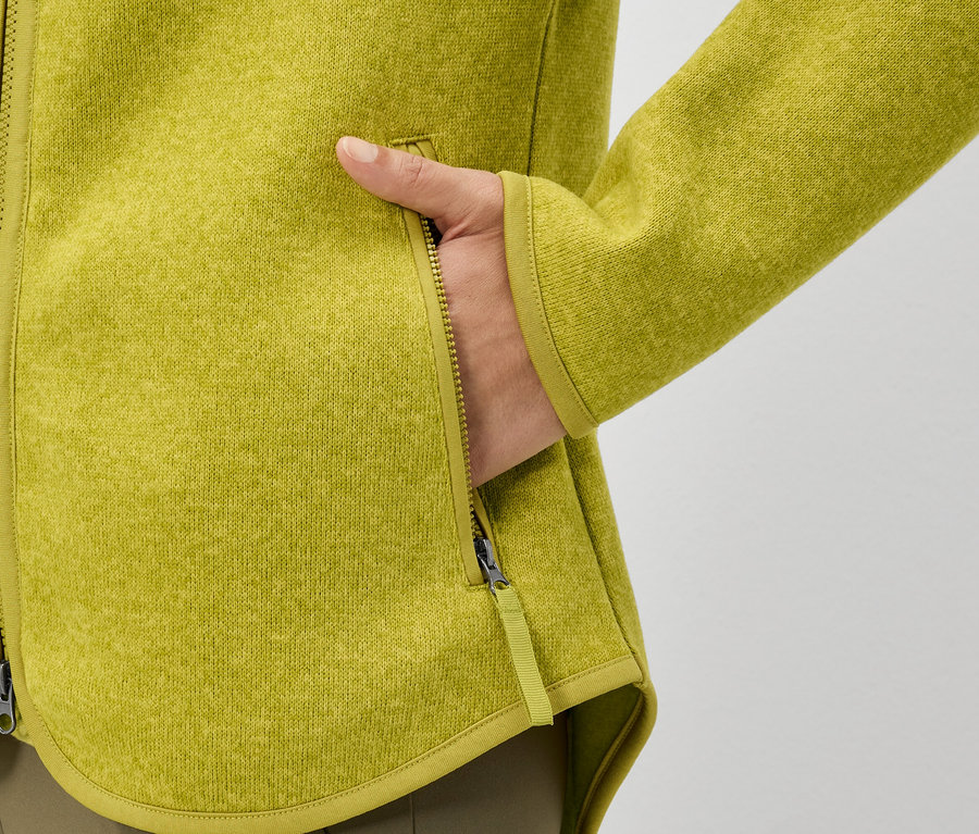 Ruka v kapse žluté fleecové bundy.