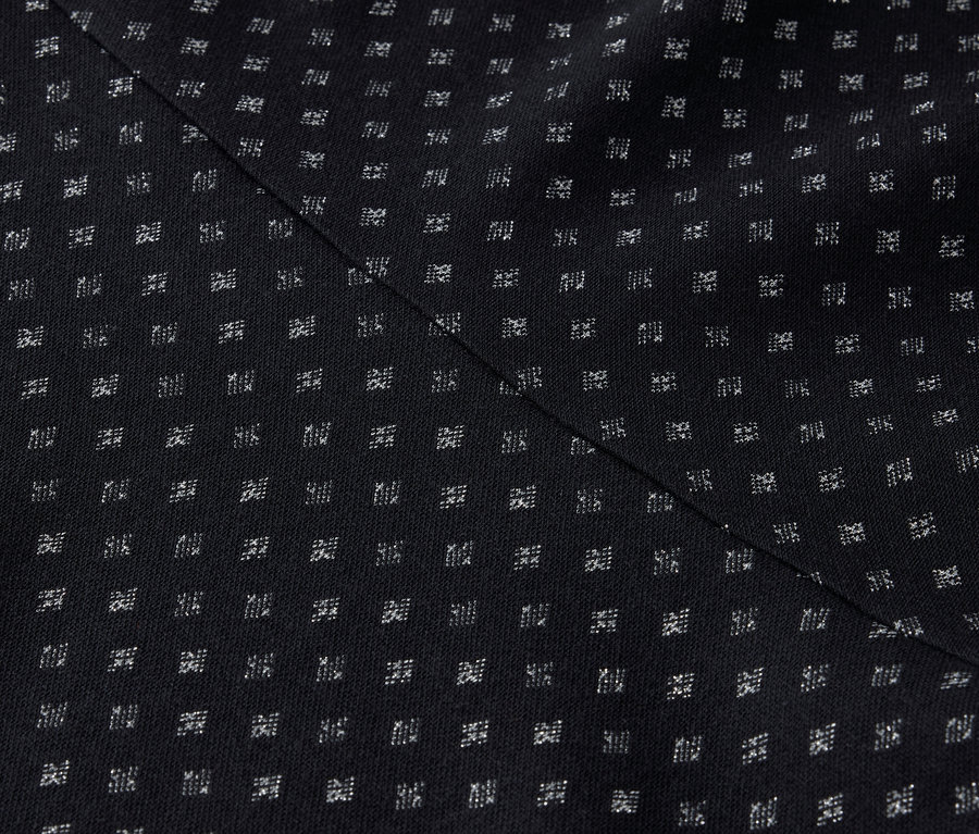 Detail černého textilu s pravidelným vzorem malých bílých čtverečků a diagonálním švem.