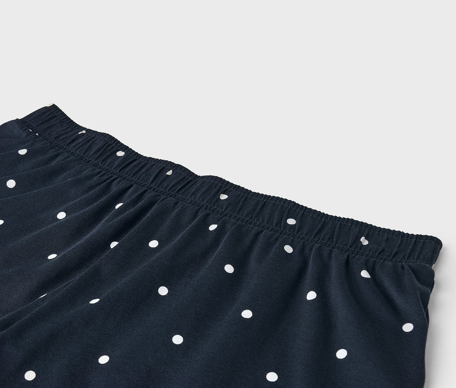 Detail navy kalhot s bílými puntíky a elastickým pasem.