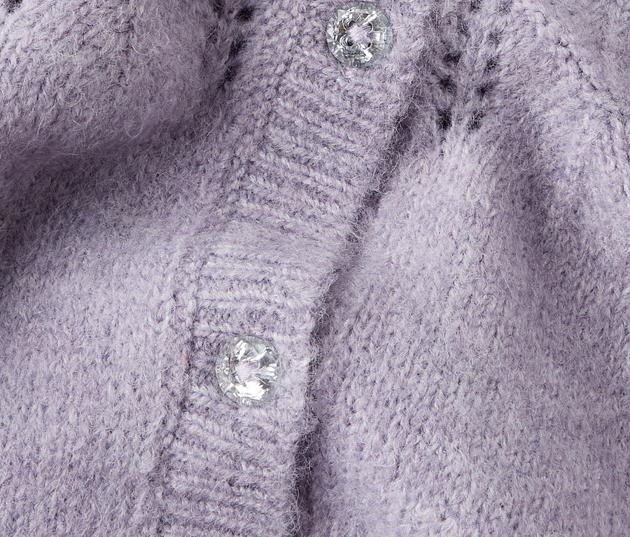 Detail fialového pleteného svetru se dvěma stříbrnými knoflíky.