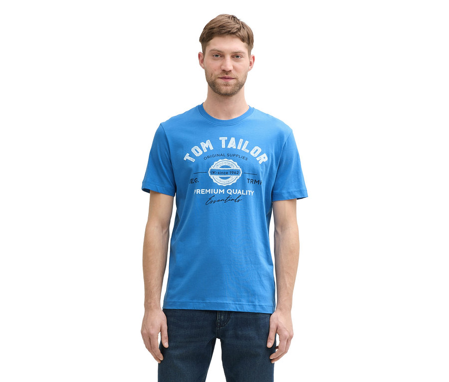 Muž má na sobě tričko s logem Tom Tailor, sapphire blue a džíny.