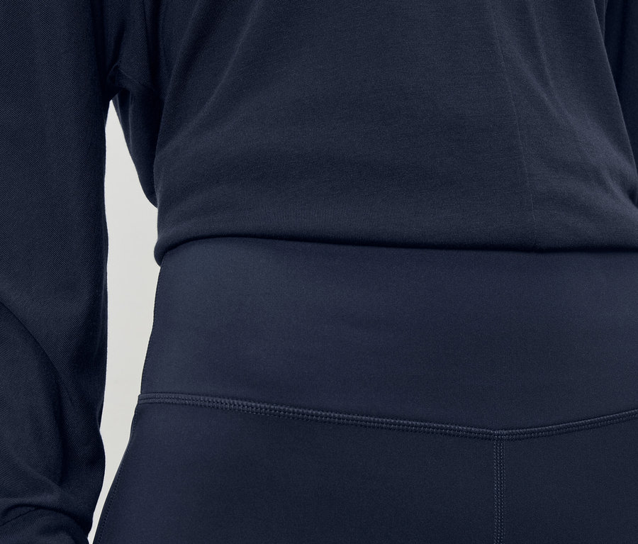 Detailní záběr na tmavě modré sportovní oblečení skládající se z topu s dlouhým rukávem a legín.