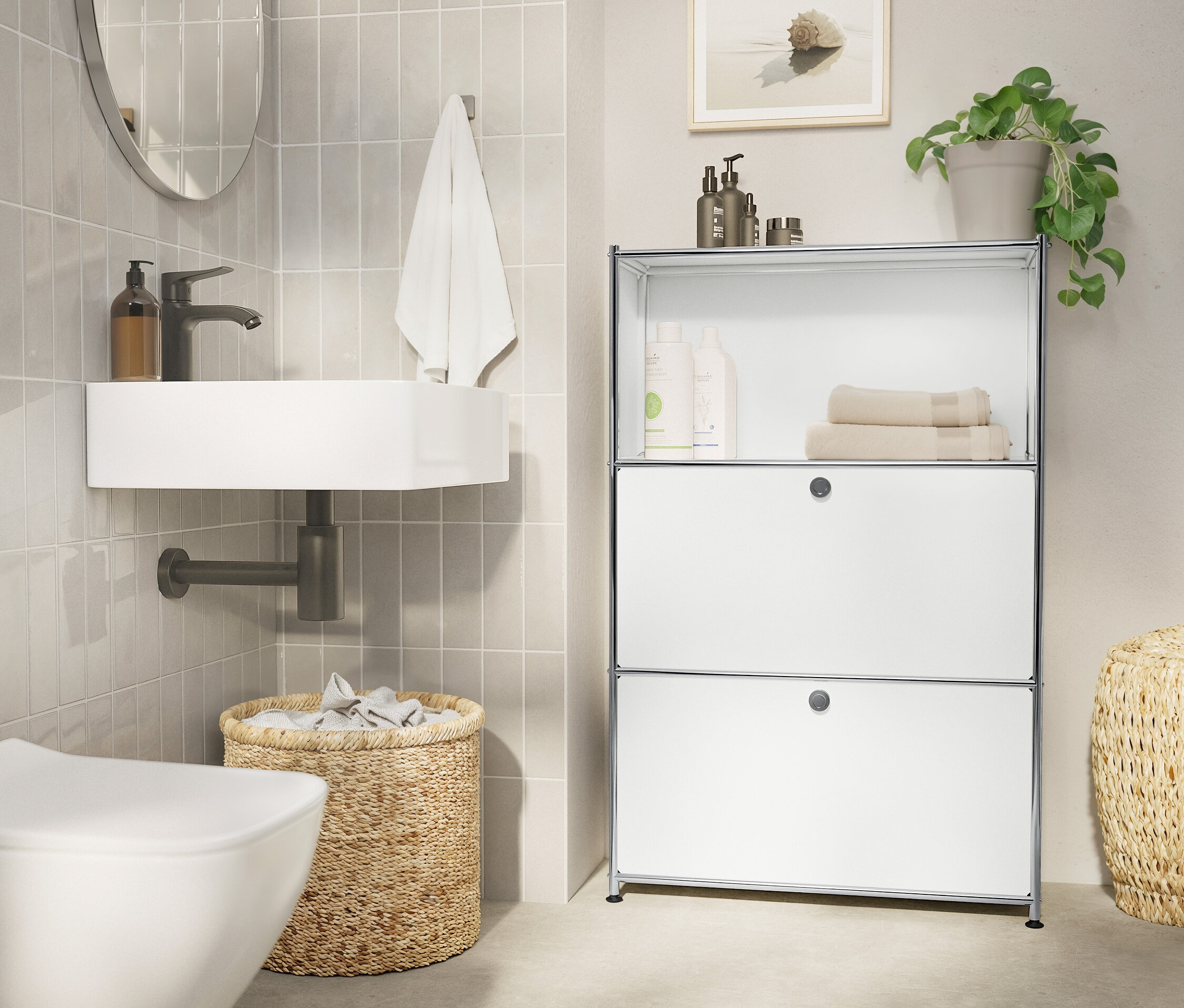 Koupelna s bílým umyvadlem, oválným zrcadlem, ručníkem, pleteným košem a bílým regálem.