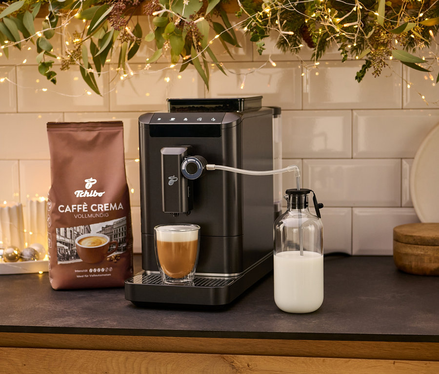 Kávovar »Esperto 2 Milk« Granite Black s šálkem kávy a balíčkem kávy Crema. Mléko je uloženo ve skleněné nádobě.