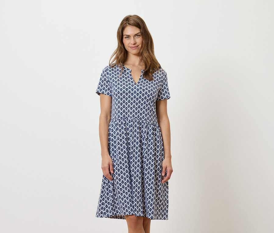 Žena stojí a má na sobě modrobílé šaty.