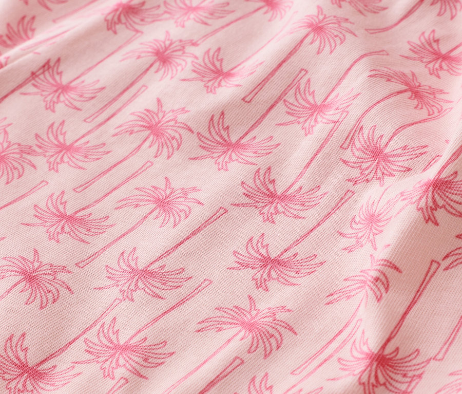 Detail růžové látky s palmovým vzorem.