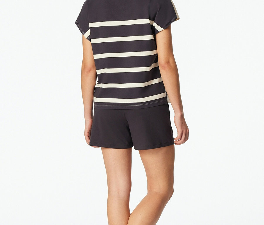 Žena zezadu v šedo-bílém pruhovaném tričku a kraťasech.