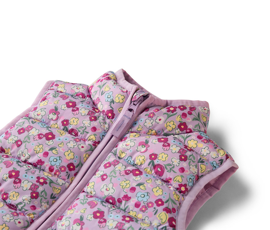 Detailní záběr na fialovou prošívanou vestu s květinovým vzorem a zipem.