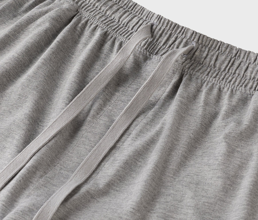 Detail šedých tepláků se stahovací šňůrkou.