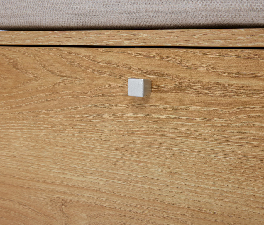 Detailní záběr na světle hnědou dřevěnou komodu se zásuvkou a stříbrnou čtvercovou úchytkou.