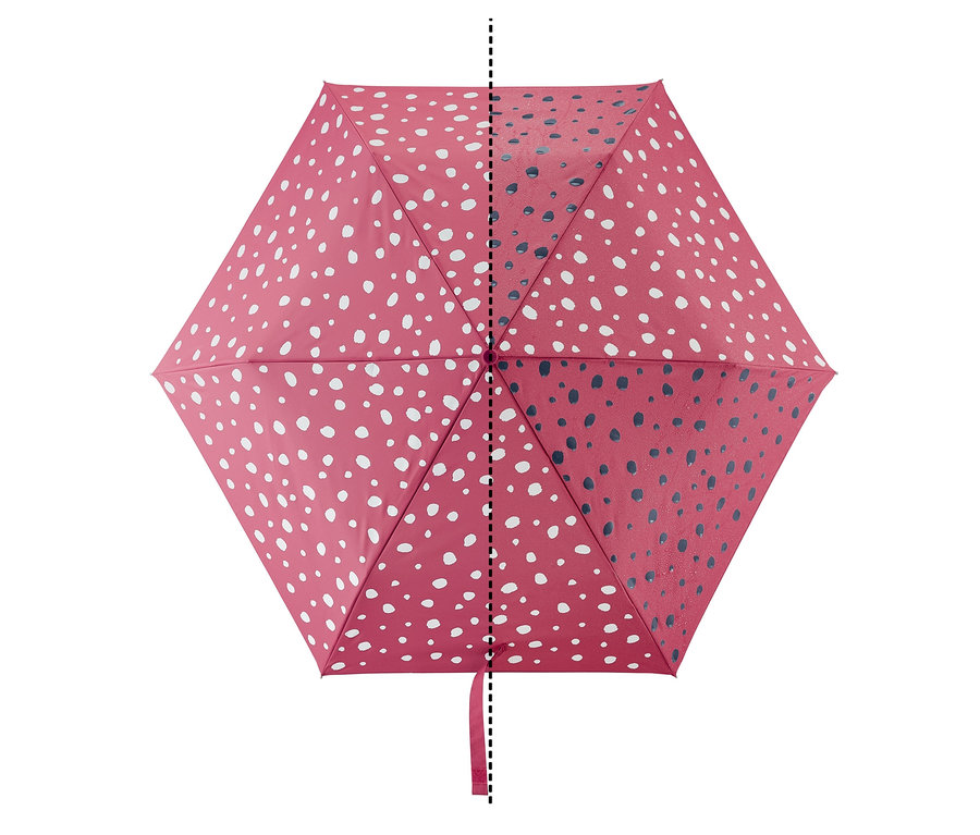 Detail dětského skládacího deštníku s efektem změny barvy, červená látka s bílými puntíky na jedné straně a tmavě modrými puntíky na druhé straně.