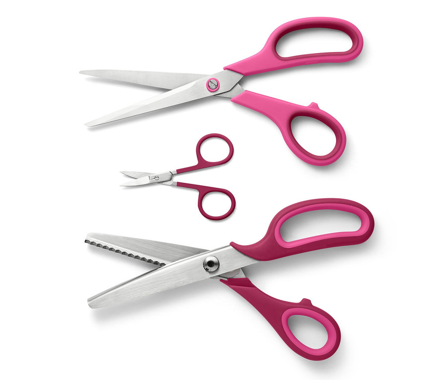 Sada nůžek na látku se třemi kusy s růžovými rukojeťmi na bílém pozadí.