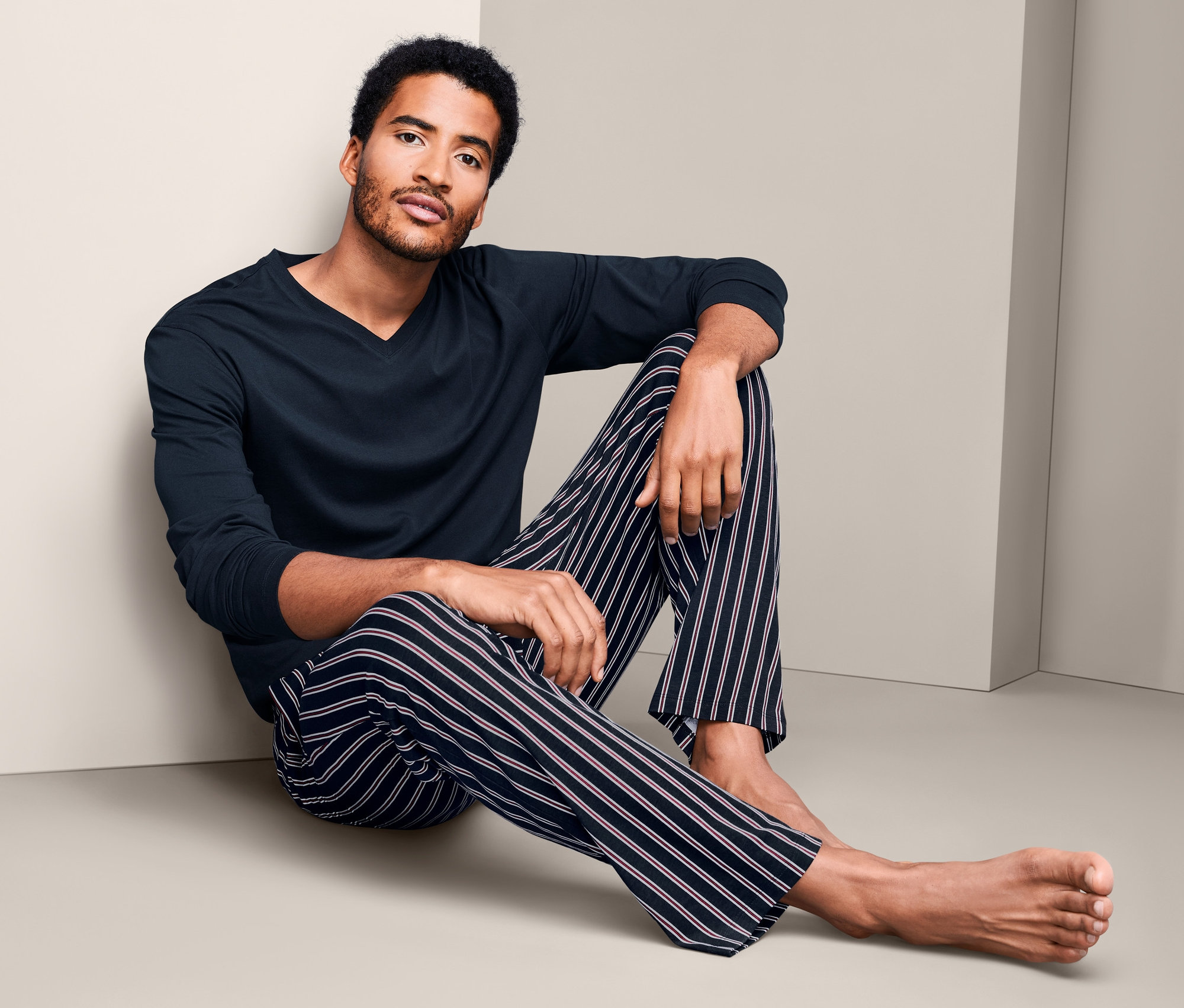 Muž sedí na podlaze v pyžamu.