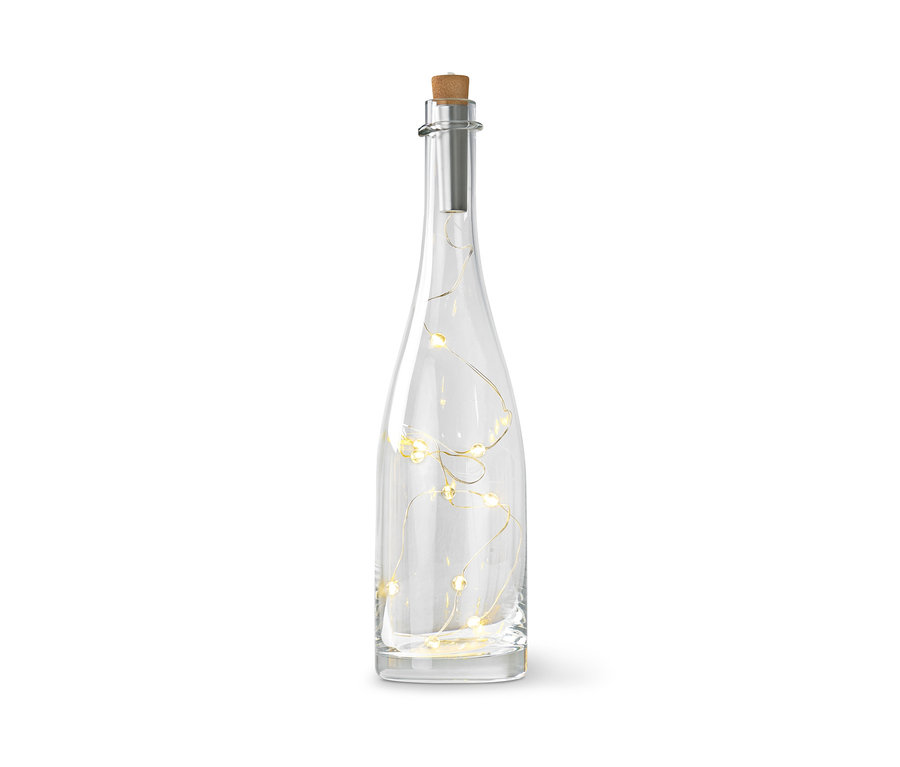 Čirá skleněná láhev s korkovou zátkou a světelným řetězem uvnitř.