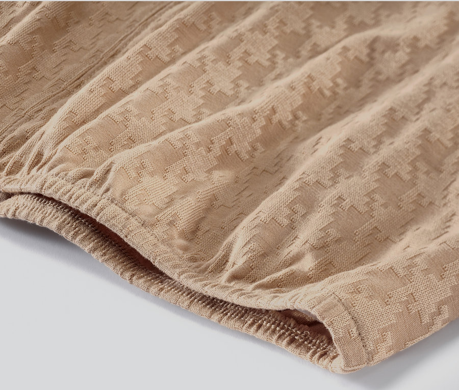 Detail strukturovaného trika s dlouhým rukávem pískové barvy.