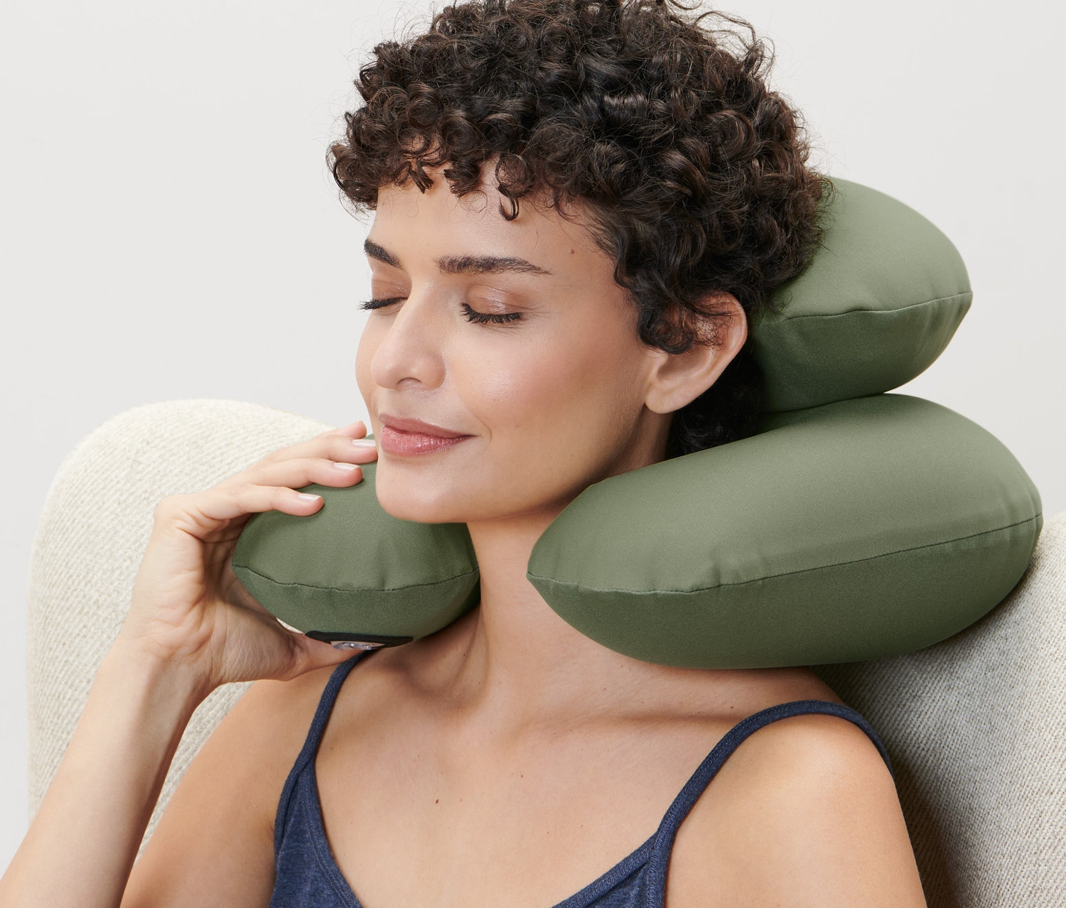 Žena sedí v křesle a používá nafukovací šíjový polštářek.