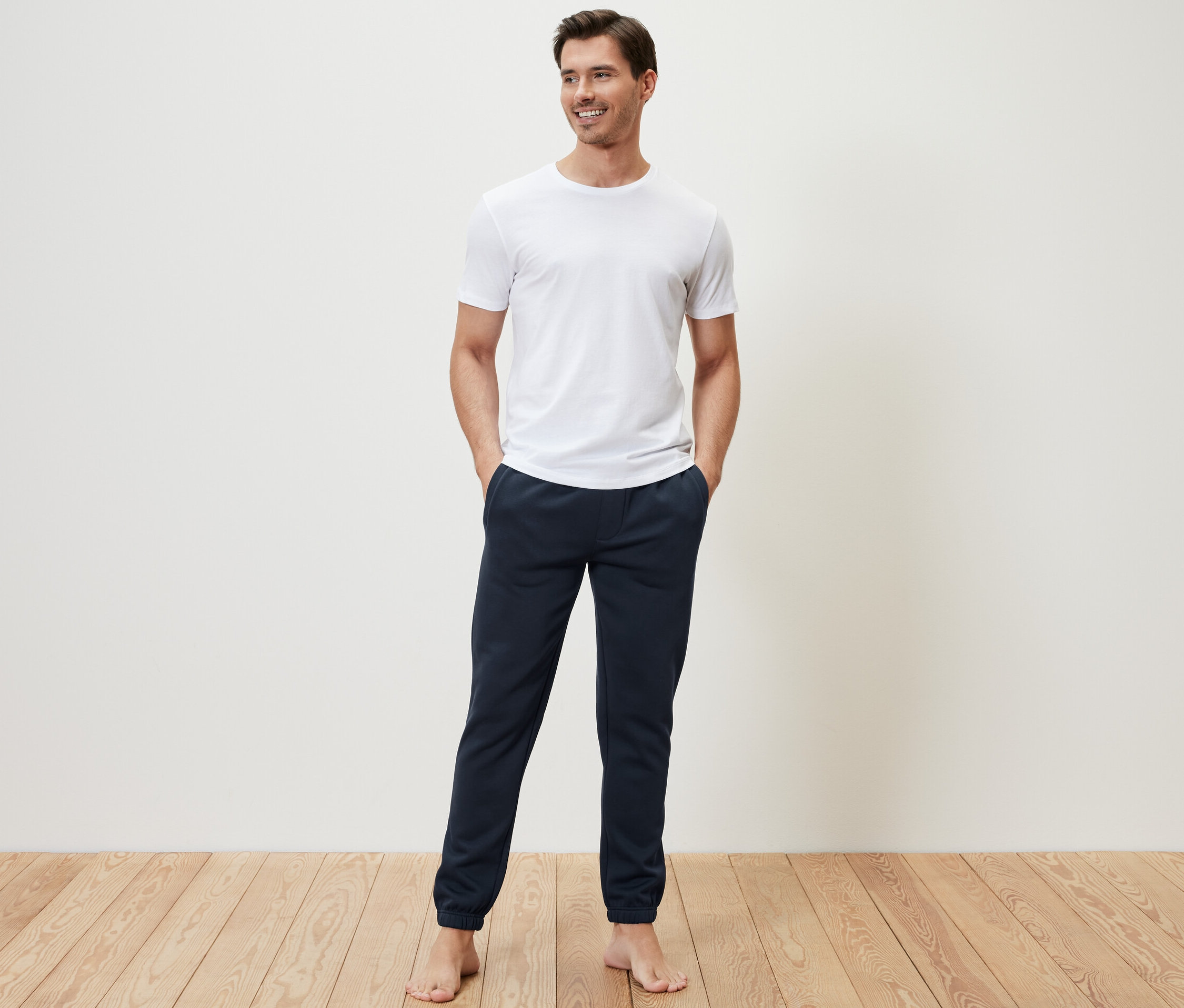 Muž stojí a má ruce v kapsách tepláků.