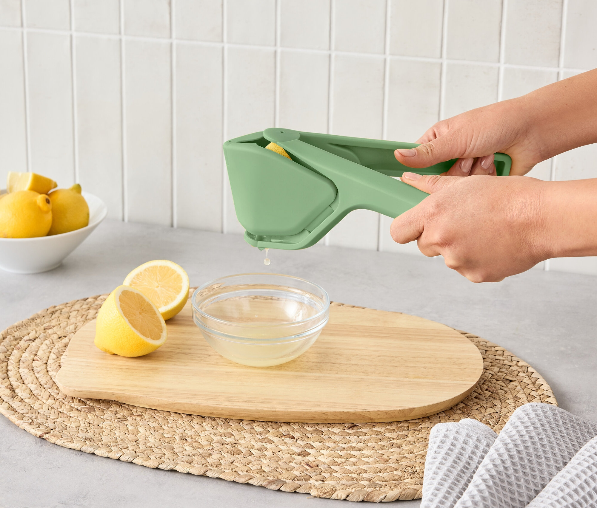 Žena používá prostorově úsporný lis na citrusy k vylisování citronu do misky.