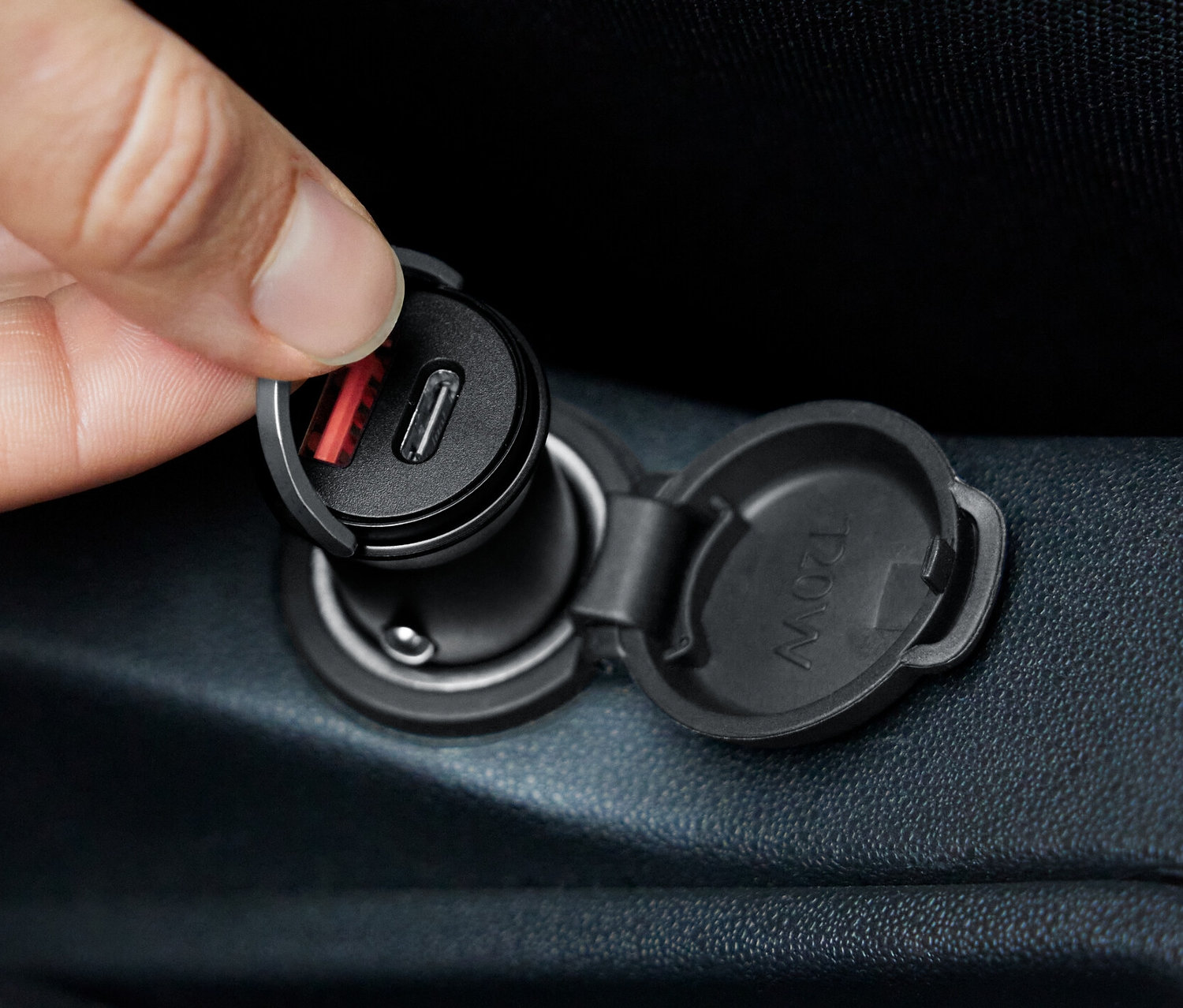 Ruka vkládá rychlonabíječku do auta do zásuvky.