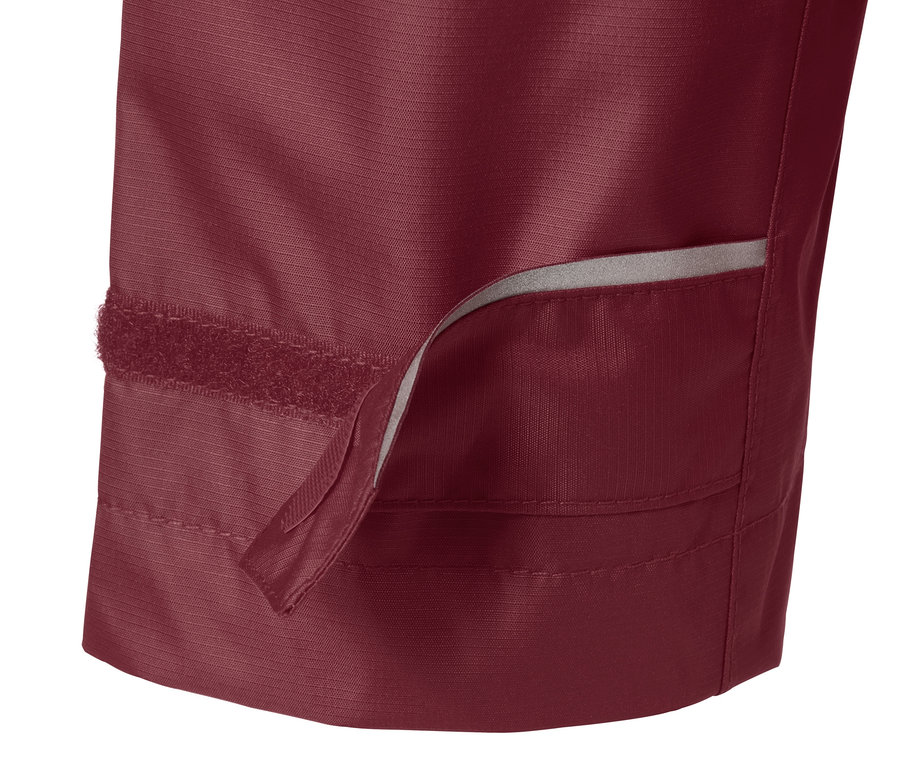 Detail vínově červené bundy do deště s viditelným zapínáním na suchý zip.