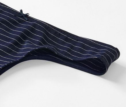 Detail modrých tang s bílými proužky a malou mašličkou.