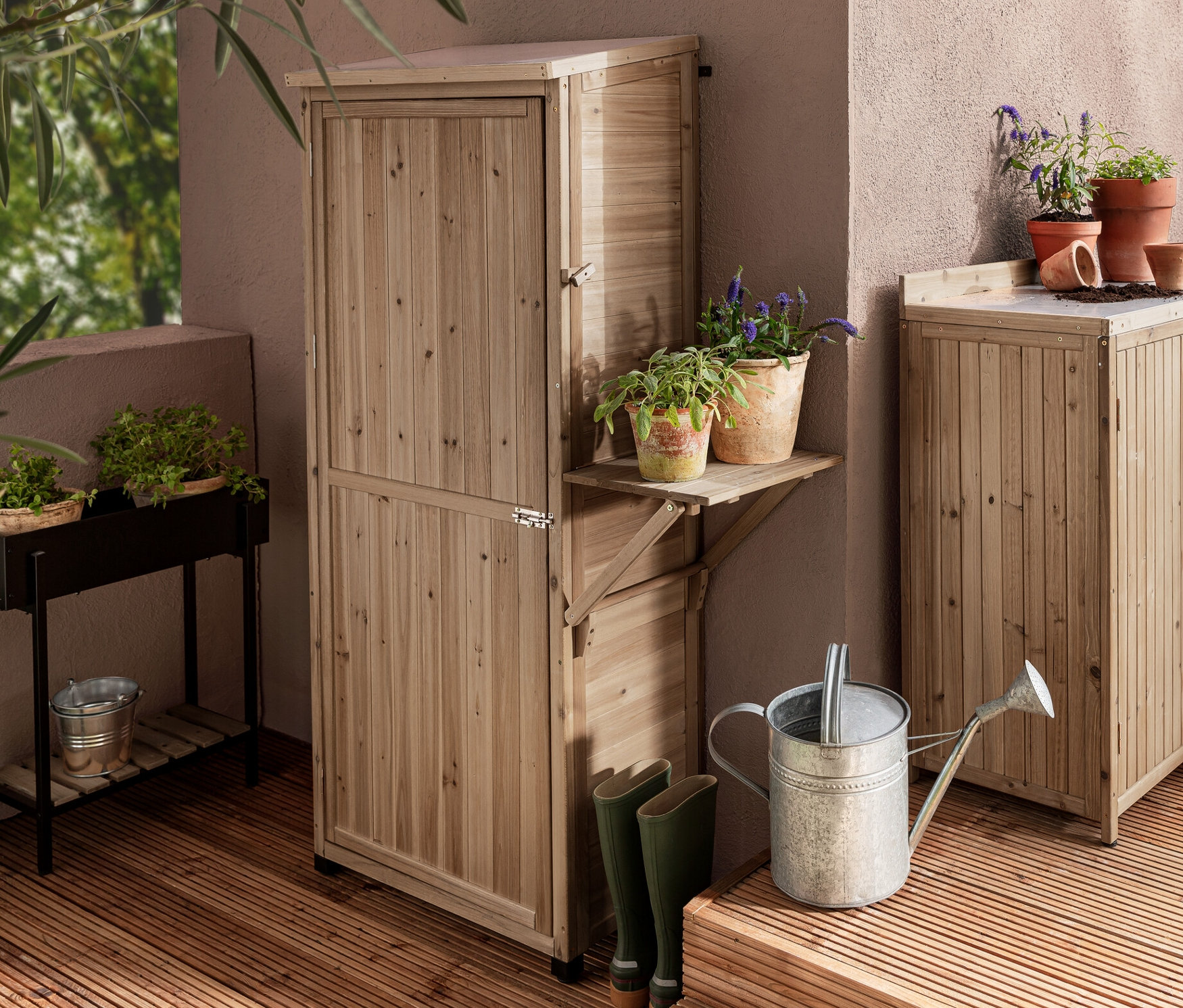 Dvě zahradní skříně »Tinus«, jedna velká s výklopnou boční policí a jedna malá, a konzola s truhlíkem »Elin« na dřevěné terase.